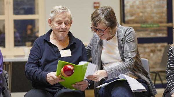 Alzheimer's Society Singing for the Brain attendees looking at a song book
